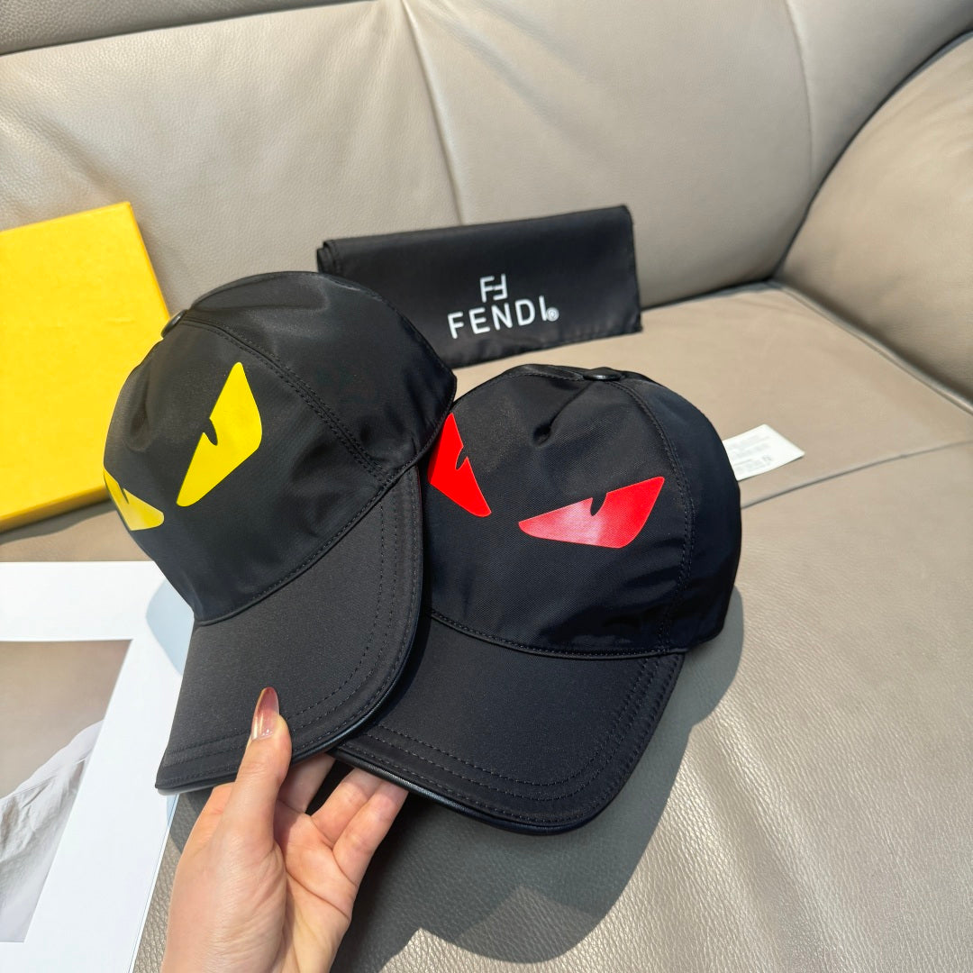 Fendi cap pair on couch: black caps with yellow and red logo graphics.