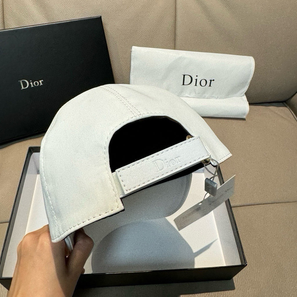 White Dior cap with curved brim and embroidered 'Dior' band label, underside visible.