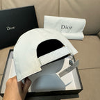 White Dior cap with curved brim and embroidered 'Dior' band label, underside visible.