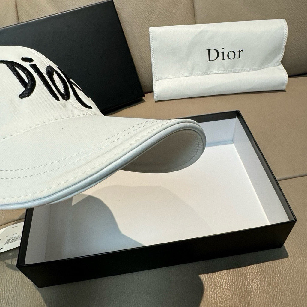 White Dior cap brim close-up with black 'Dior' lettering and topstitching.