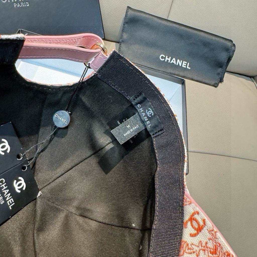Black logo baseball cap with pink trim and adjustable strap, CHANEL labels visible