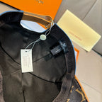 Black monogram cap underside with strap, hanging tags, and center label