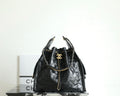 Black Chanel bag with quilted leather, chain handles, and gold CC logo at top