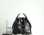 Black Chanel bag with quilted leather, chain handles, and gold CC logo at top