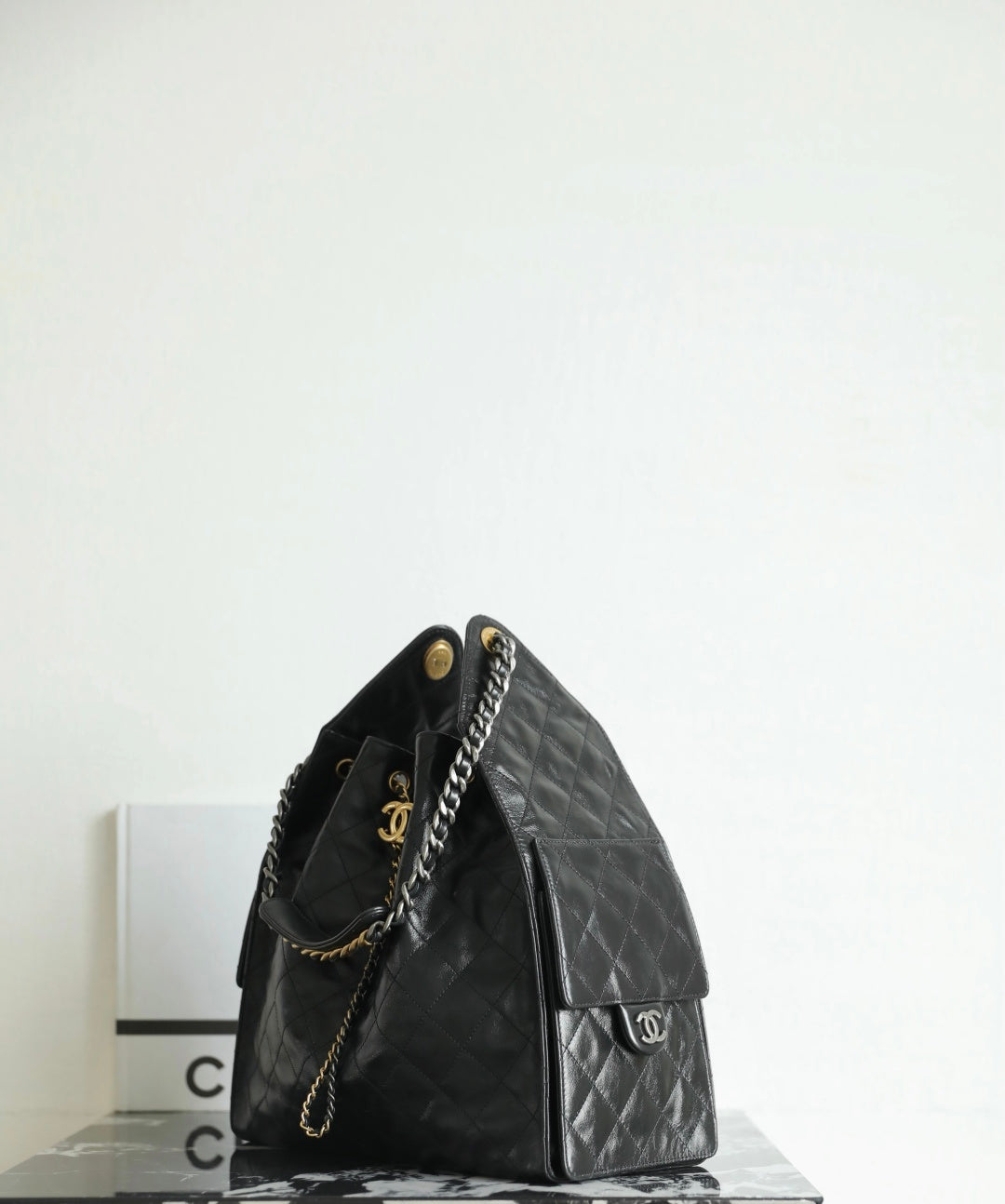 Black Chanel bag with quilted leather, short handles, and side zip pocket