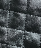 Black quilted leather close-up with stitched diamond panels