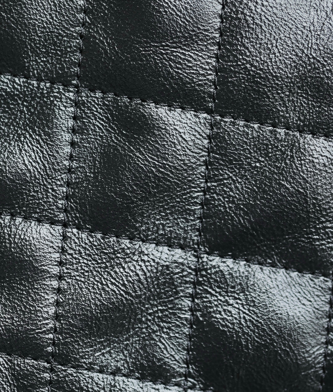Black quilted leather close-up with stitched diamond panels
