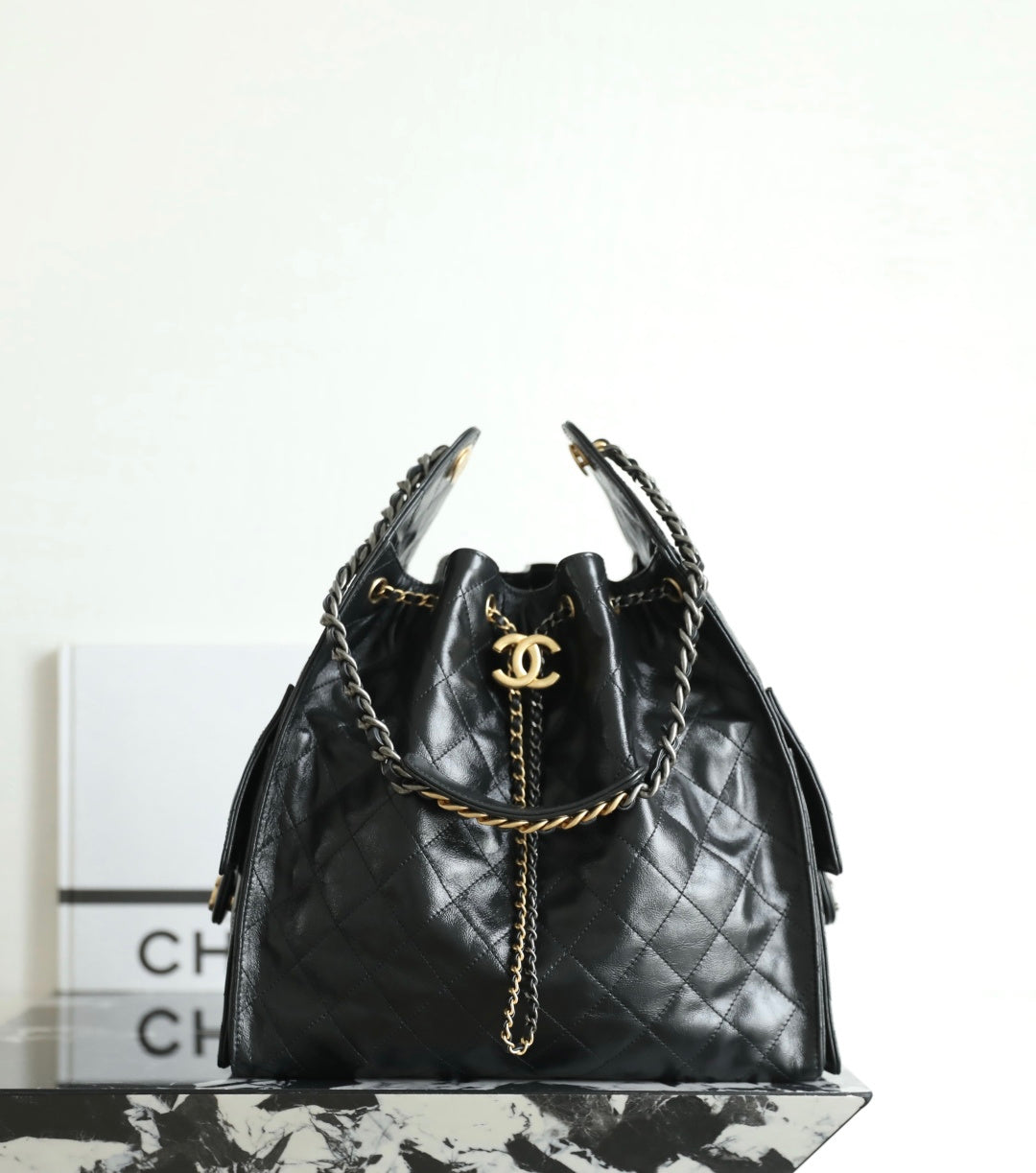 Black Chanel bag with quilted leather, braided chain shoulder strap, and gold CC emblem