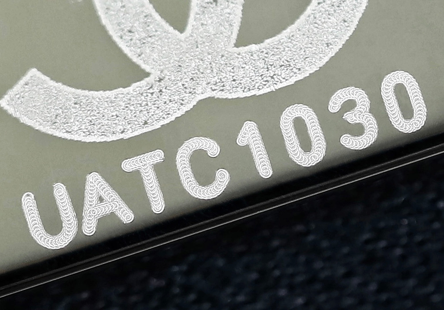 Dark leather tab with white embroidered-style serial text