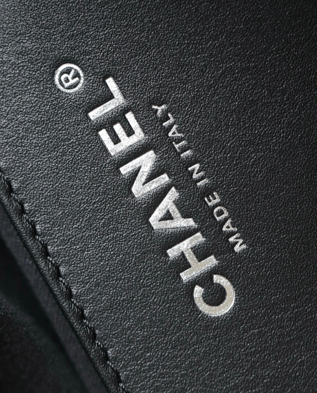 Black leather close-up with Chanel logo lettering and stitched trim