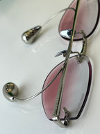 Glasses side view with black-and-gold frame and pink tinted lenses