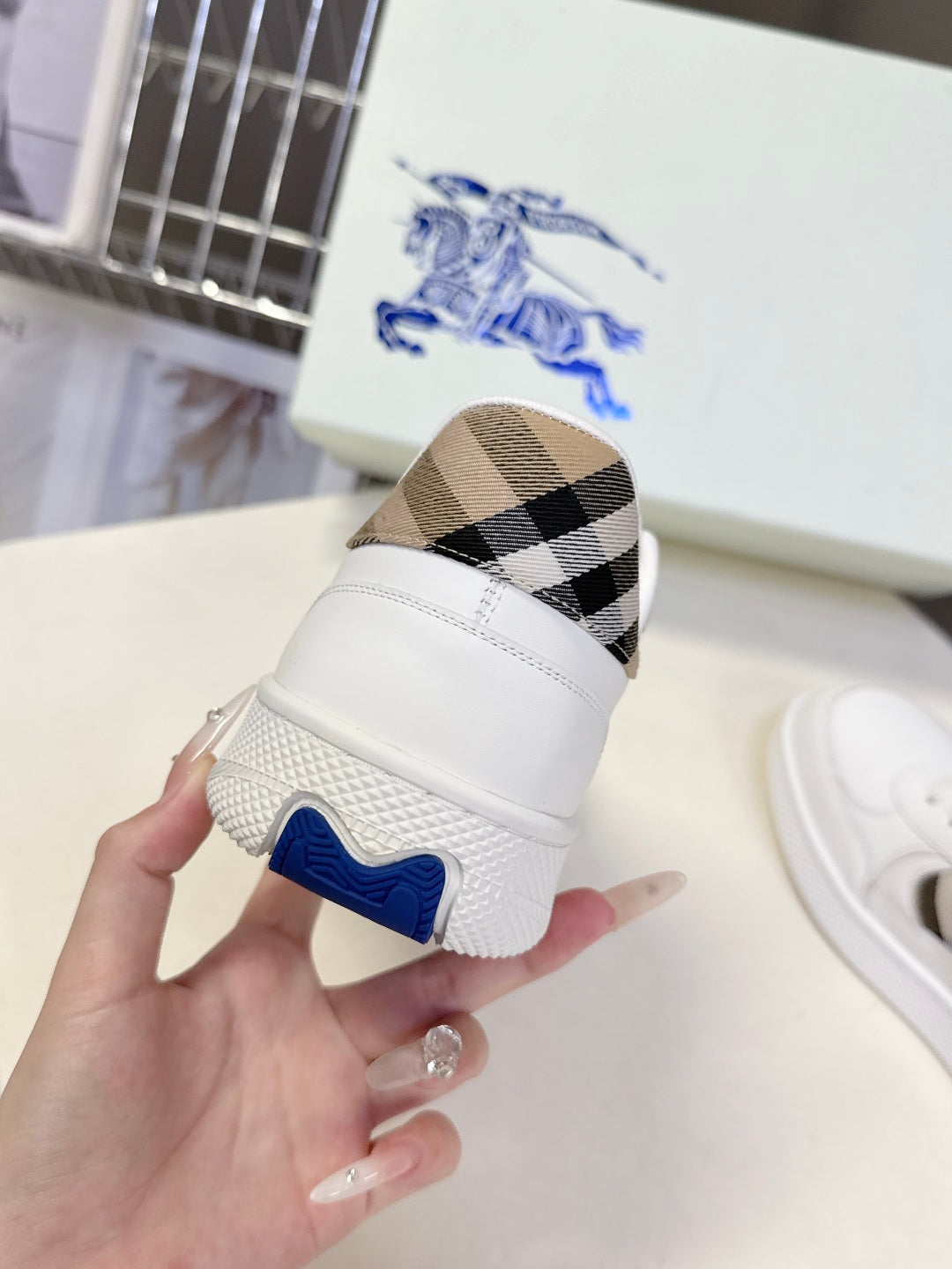 White low-top sneakers with blue logo heel detail and check-pattern side panel