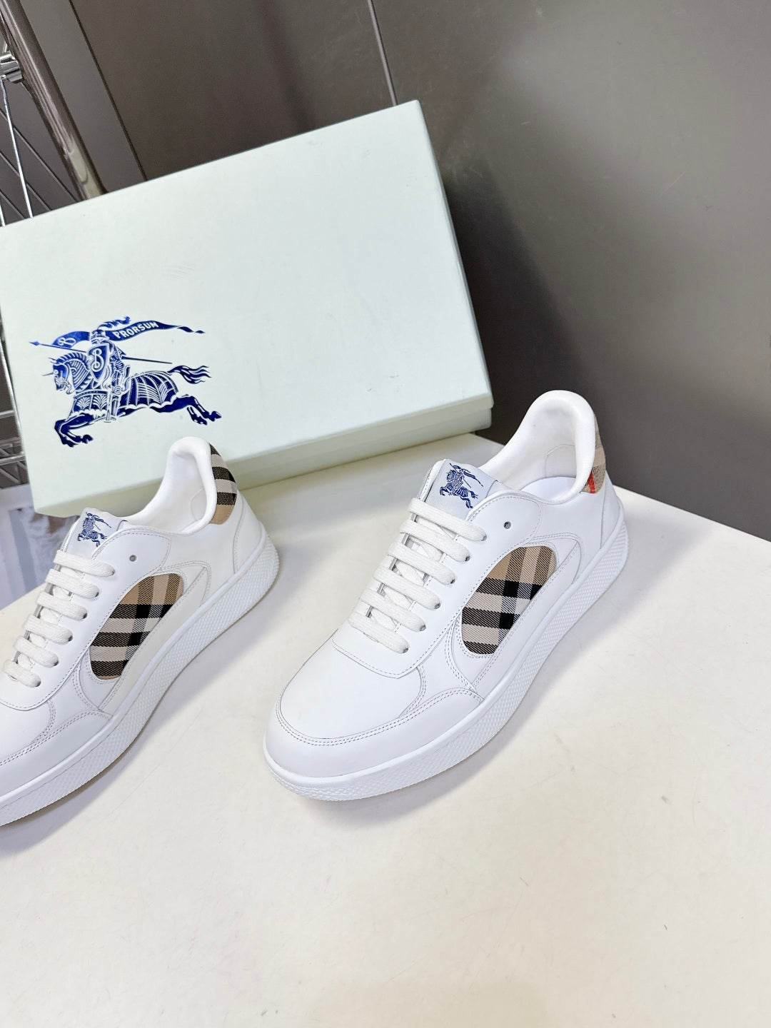 Pair of white low-top sneakers with check-pattern side panels and blue logo