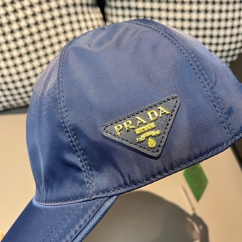 Prada blue baseball cap close-up with PRADA logo patch and curved brim.