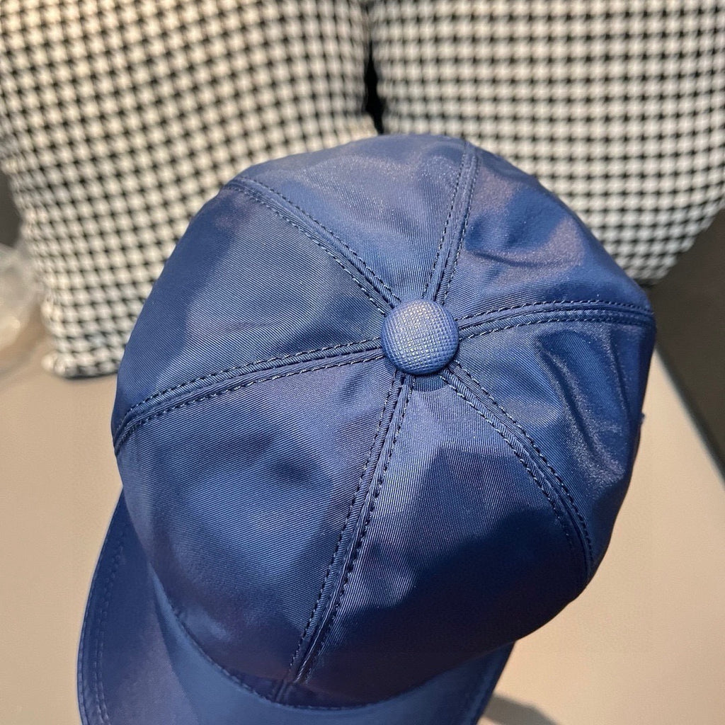 Prada blue baseball cap top view with round crown button and curved brim.