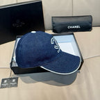 Denim baseball cap with white-edged brim and white Chanel logo on side profile.