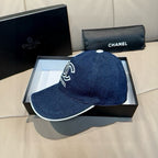 Denim baseball cap with white-edged brim and white Chanel logo on front.