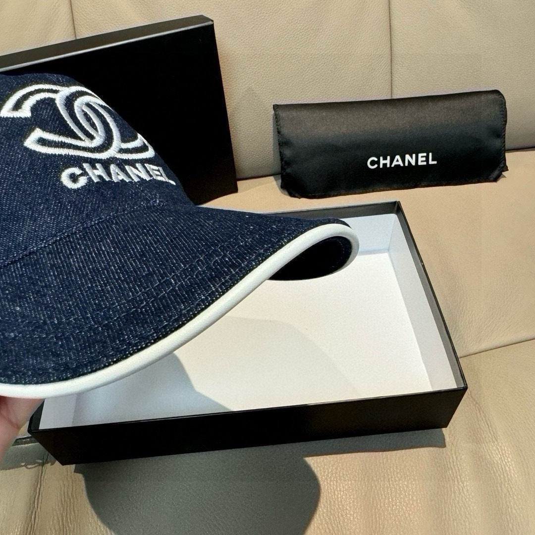 Denim baseball cap with white-edged brim and white Chanel logo; front close-up.