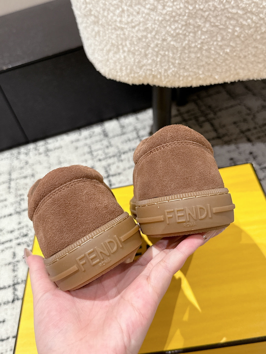 Brown suede Fendi sneakers heel close-up, hands holding the pair
