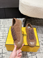 Brown suede Fendi sneakers close-up, hand holding the front and lace area