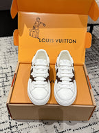 White low-top sneakers with brown monogram-style side panels and white laces