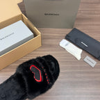 Black plush slide sandals with red logo detail, close-up strap view