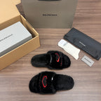 Black plush slide sandals with red logo outline, angled side view