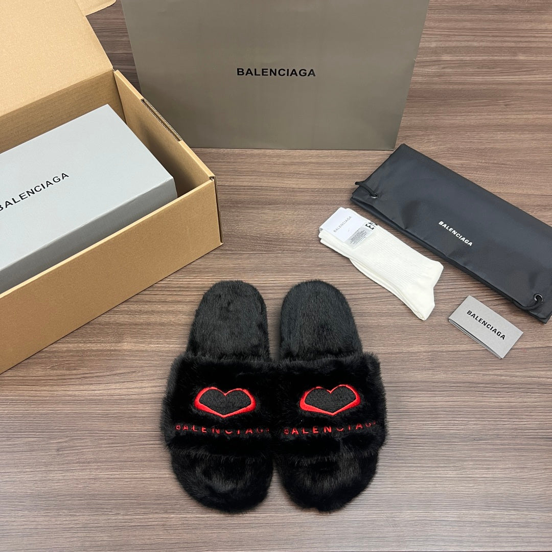 Black plush slide sandals with red heart-style logo detail, crossover front