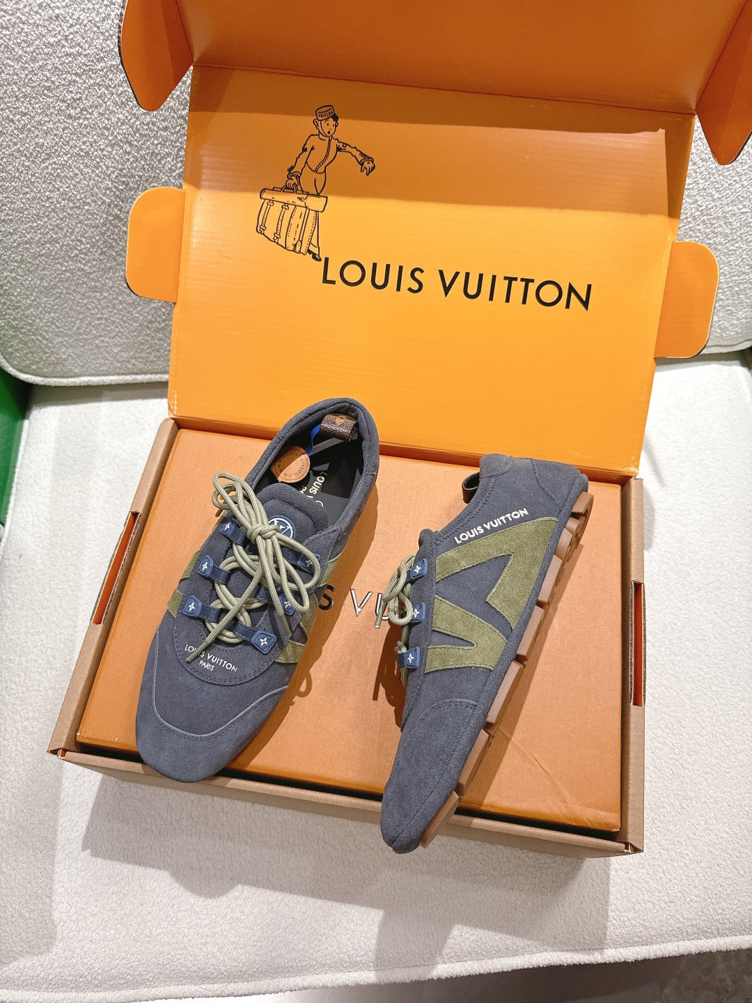 Unisex blue-gray lace-up sneakers with green geometric side panel, shown in open shoebox