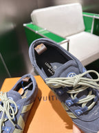 Blue-gray lace-up sneaker showing padded collar and light laces, with logo on tongue