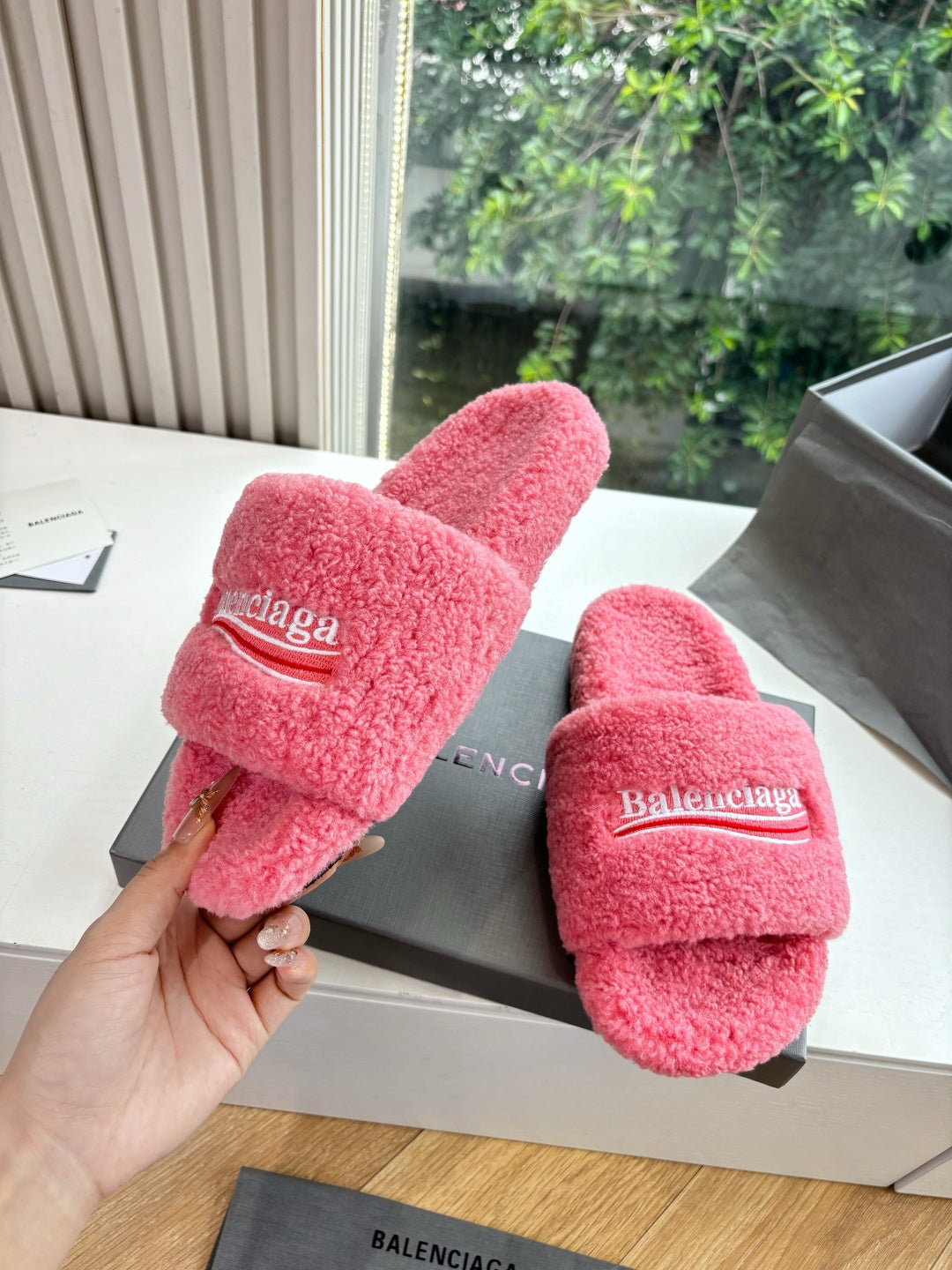 Balenciaga pink fuzzy slide sandals in hand with matching pair on box