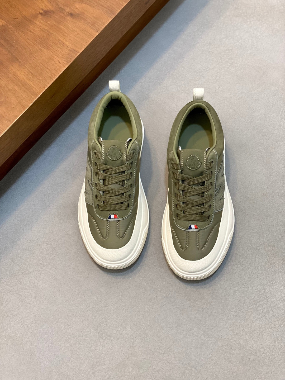 Olive low-top sneakers with white rubber sole, lace-up front, logo patch detail