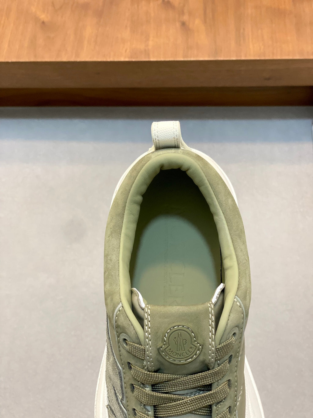Olive sneaker tongue and laces close-up with circular emblem logo