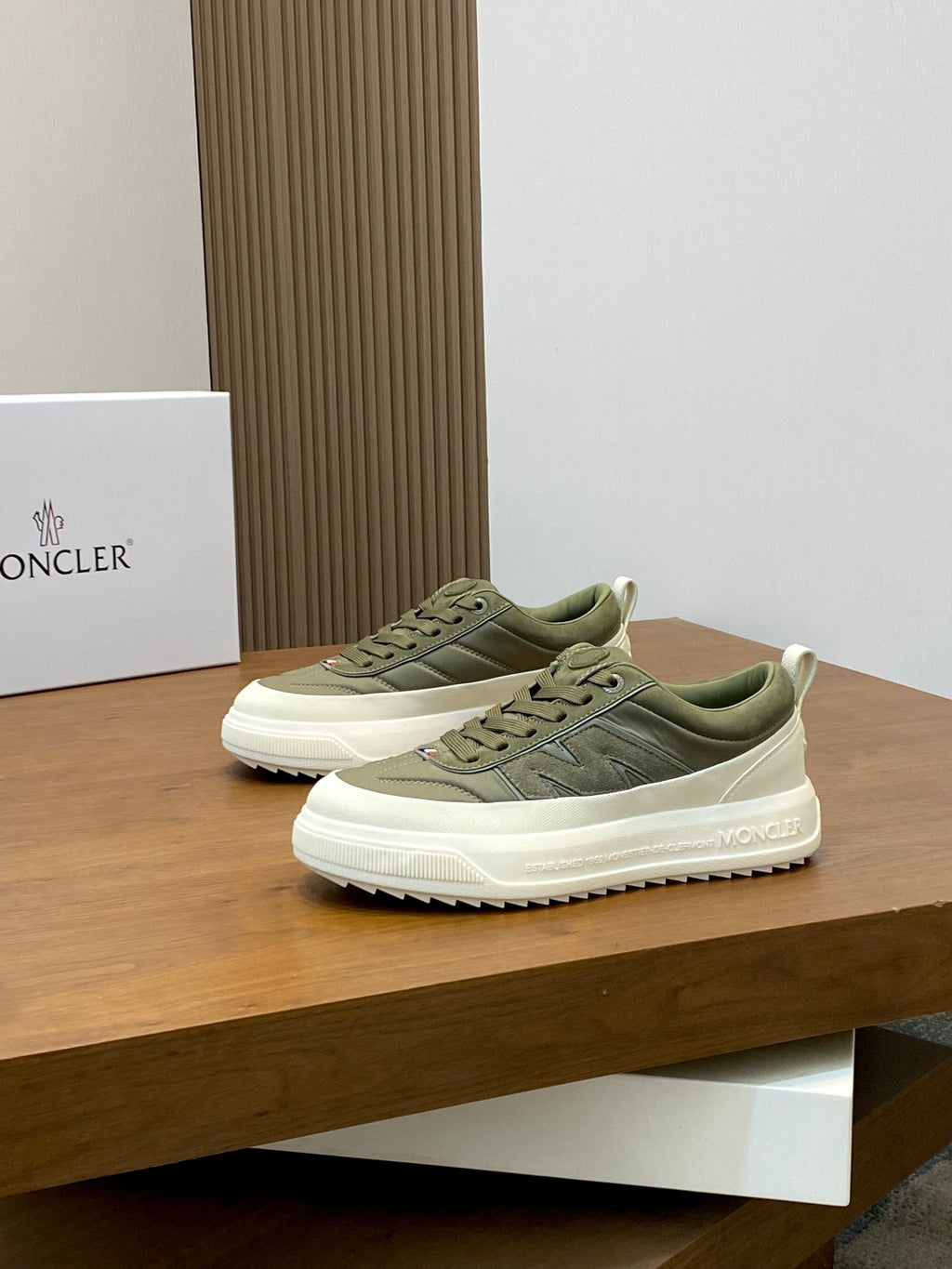 Olive low-top sneakers on display with white rubber midsole and Moncler side branding