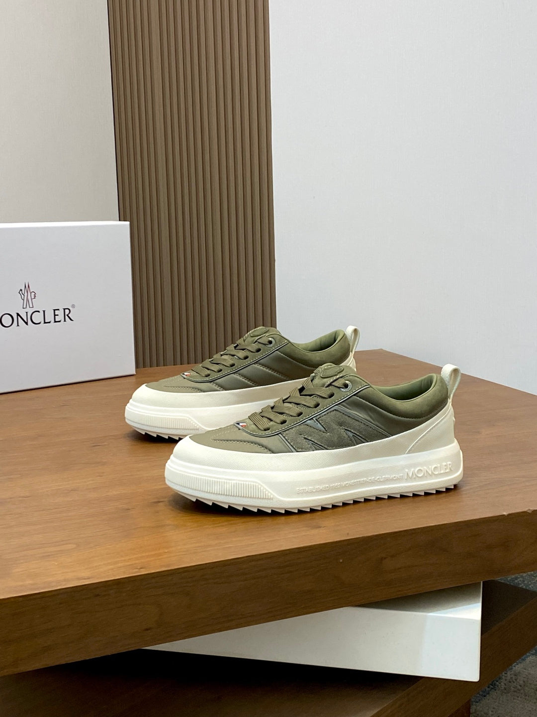 Olive low-top sneakers on display with white rubber midsole and Moncler side branding