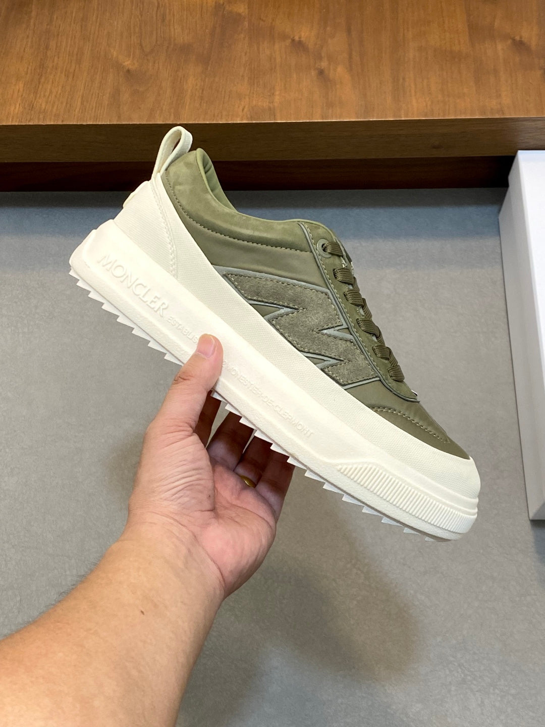 Olive lace-up sneakers close-up, white sole and Moncler script on side panel