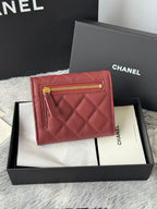 Small quilted red wallet bag with front flap and gold zip pull