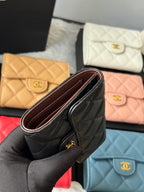 Black quilted small flap wallet held open, showing interior and gold-tone hardware