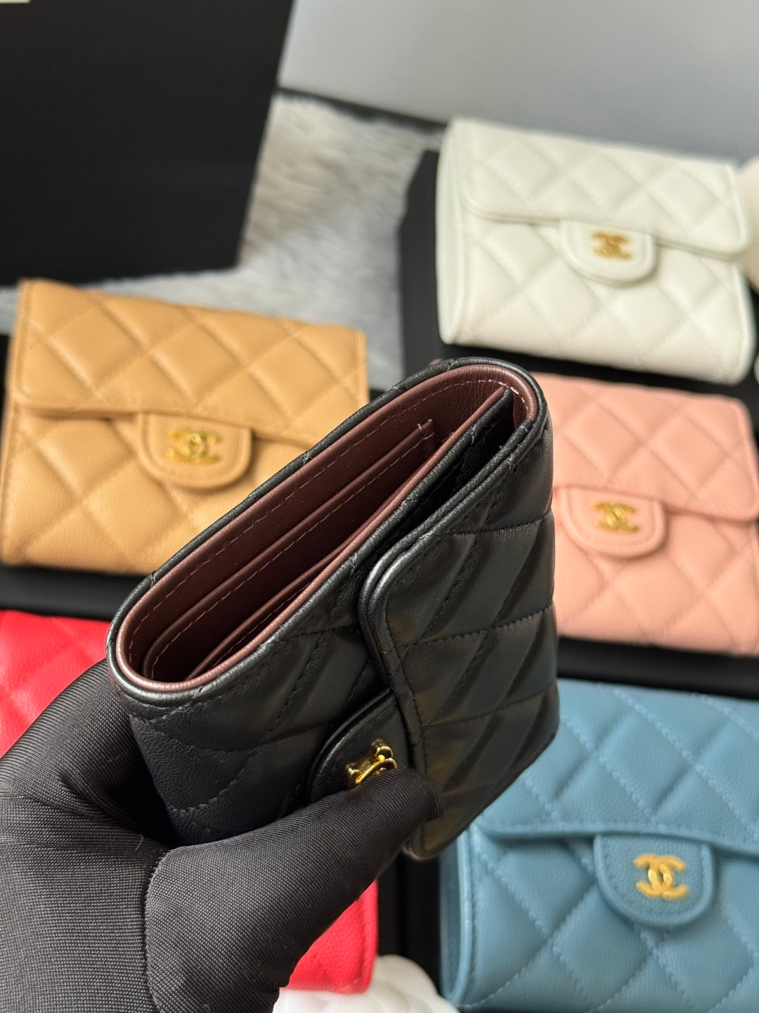Black quilted small flap wallet held open, showing interior and gold-tone hardware