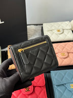 Black quilted small zip wallet with gold zipper and stitched strap