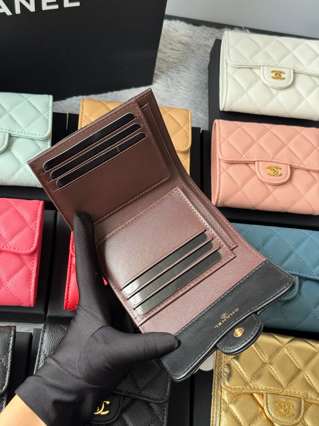 Brown leather-look card wallet with gold-tone rails and CHANEL on exterior