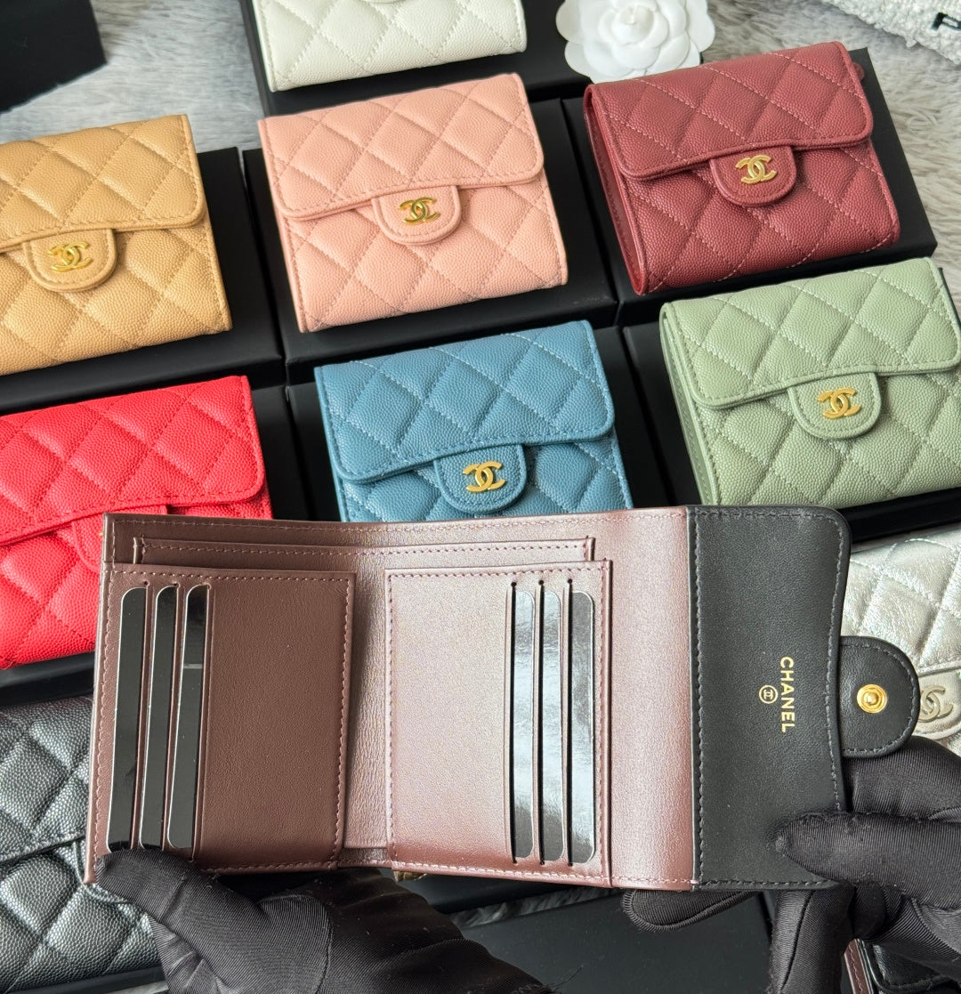 Gray card wallet with gold button and CHANEL text, open to card slots