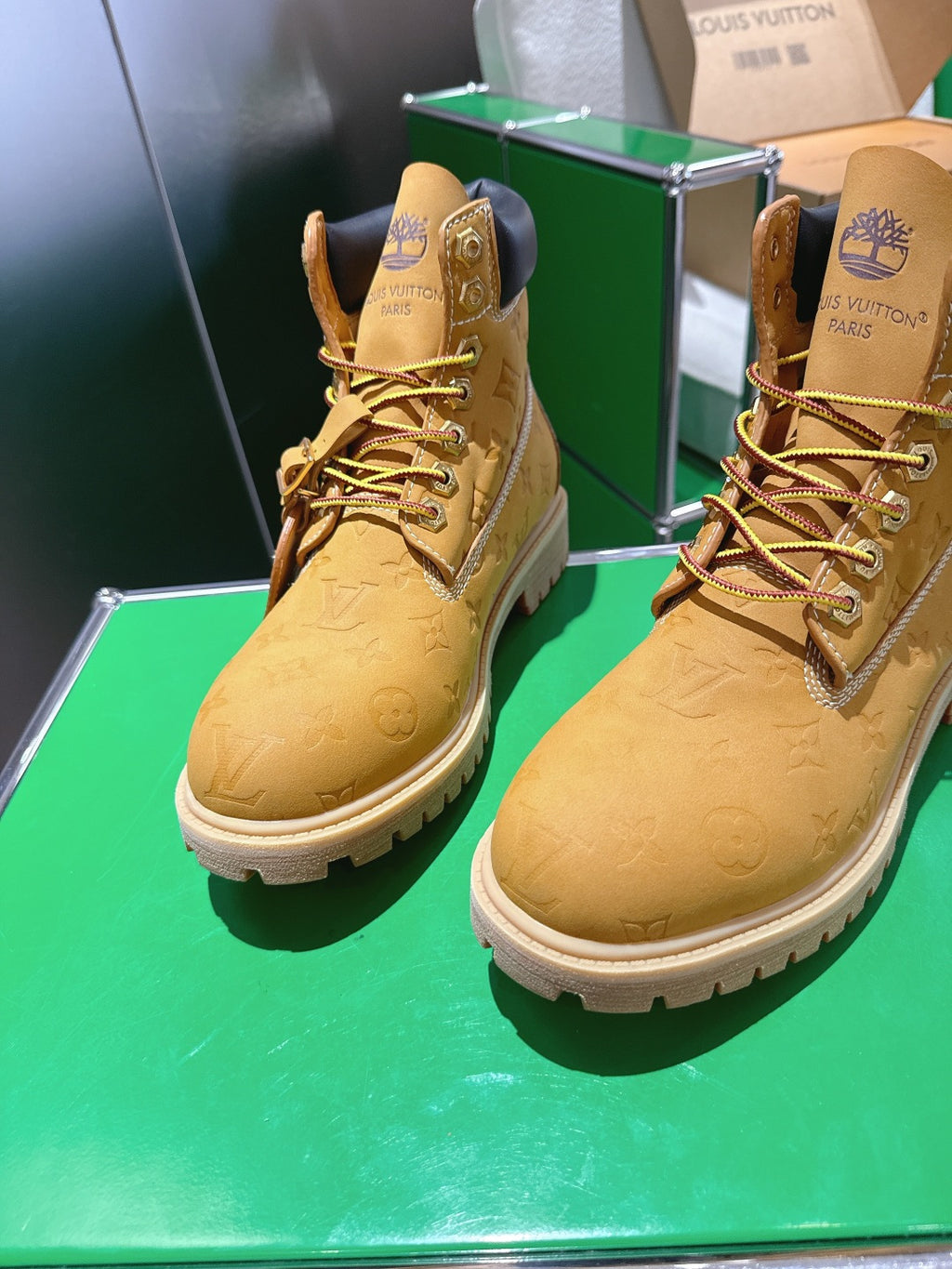 Pair of tan lace-up boots with embossed pattern, dark collar, on green platform