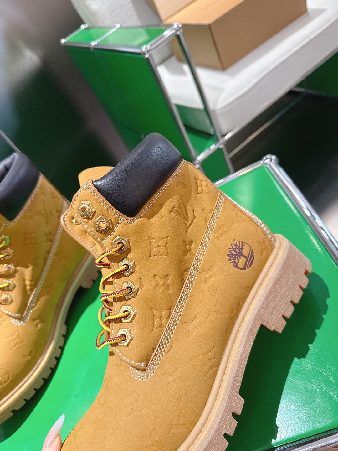 Close-up tan lace-up boot with embossed pattern, dark ankle collar, and thick tread