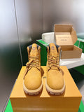 Tan lace-up boots with embossed pattern and dark ankle collar, on display