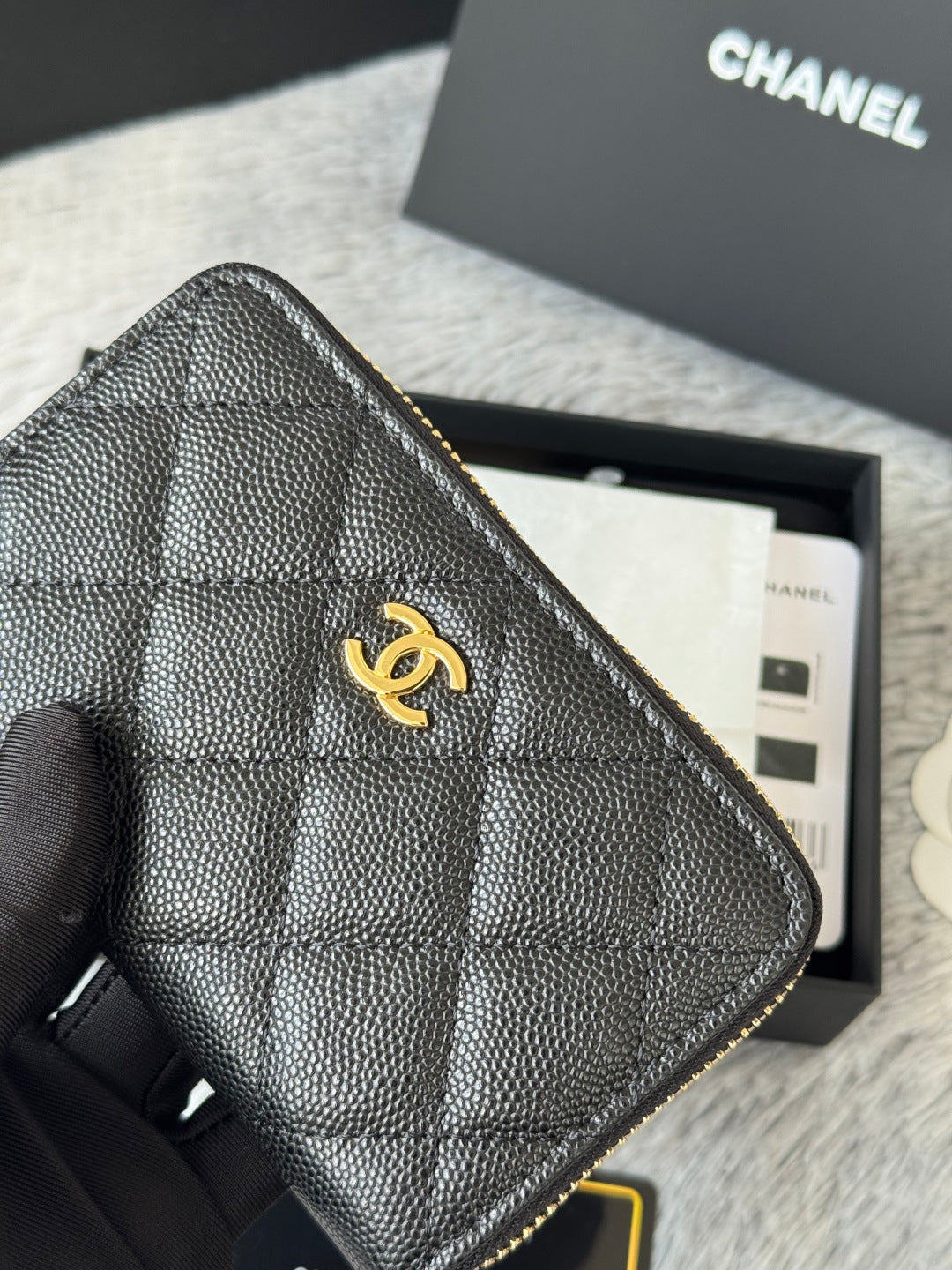 Small quilted bag corner close-up with CC logo and gold-tone zipper edge