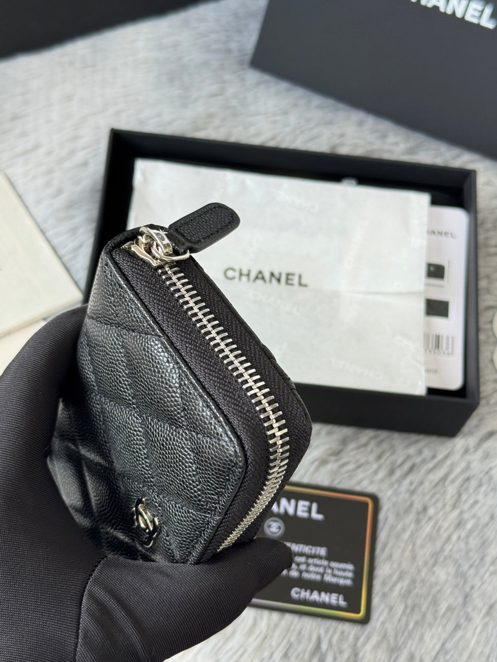 Chanel small bag with zip closure, textured dark black leather, close-up side.