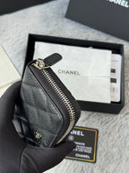Chanel small bag with zip closure, textured dark black leather, close-up side.