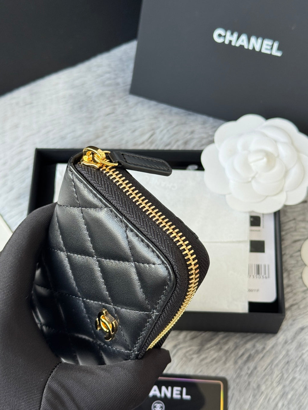 Small quilted zip wallet side view, dark leather with gold-tone zipper