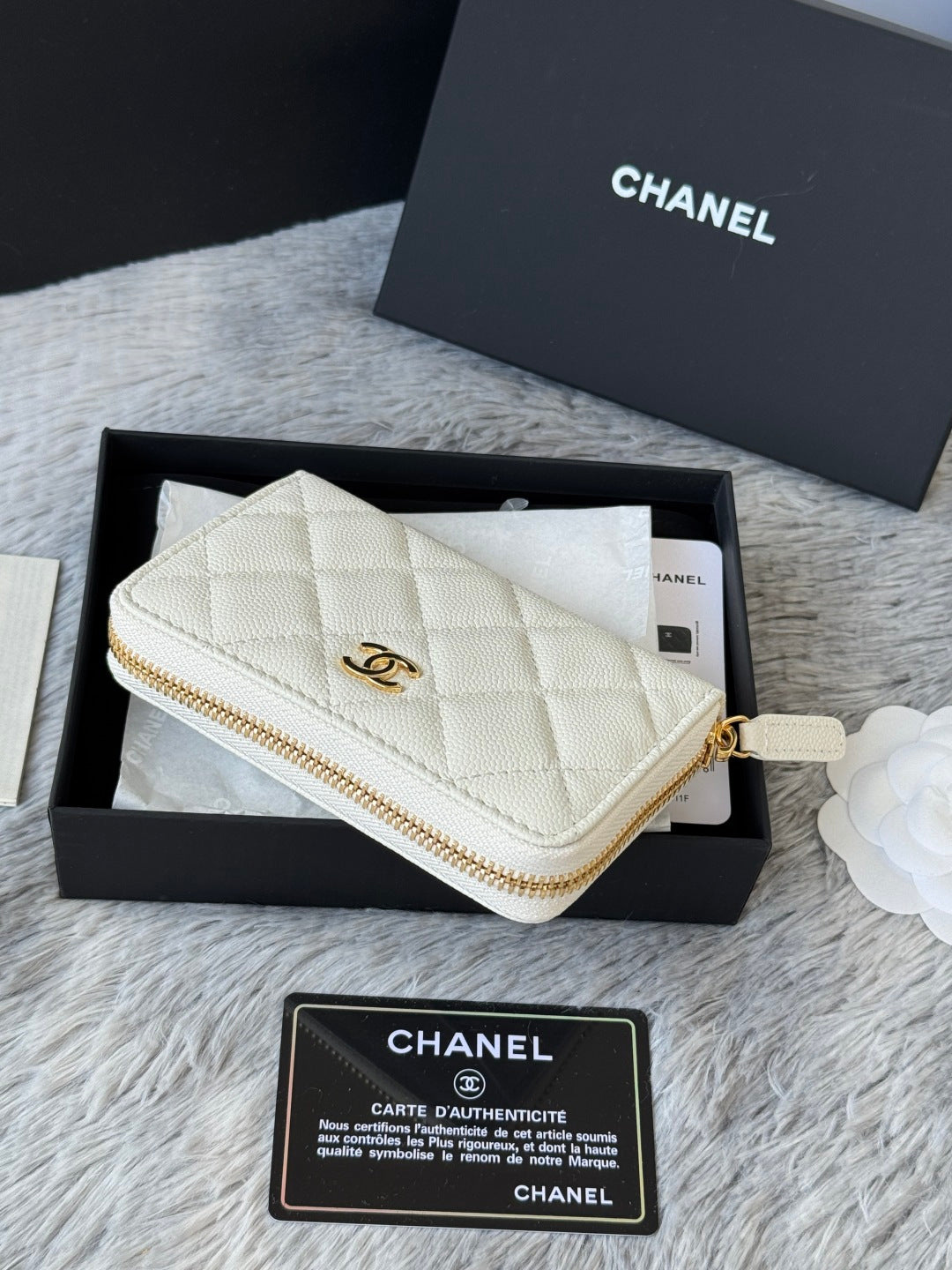 White quilted small bag with gold wrist strap and gold-tone zipper detail